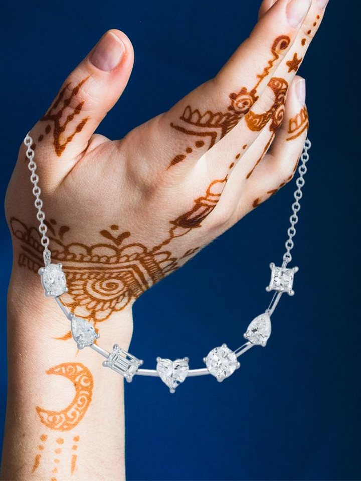 Multi-shape station necklace held in a hennaed hand